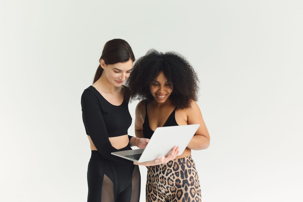 Two women smiling as they work together on a laptop