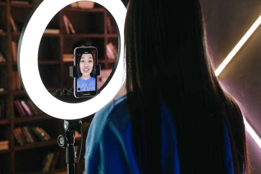 A creator recording a video with her face visible on the phone screen