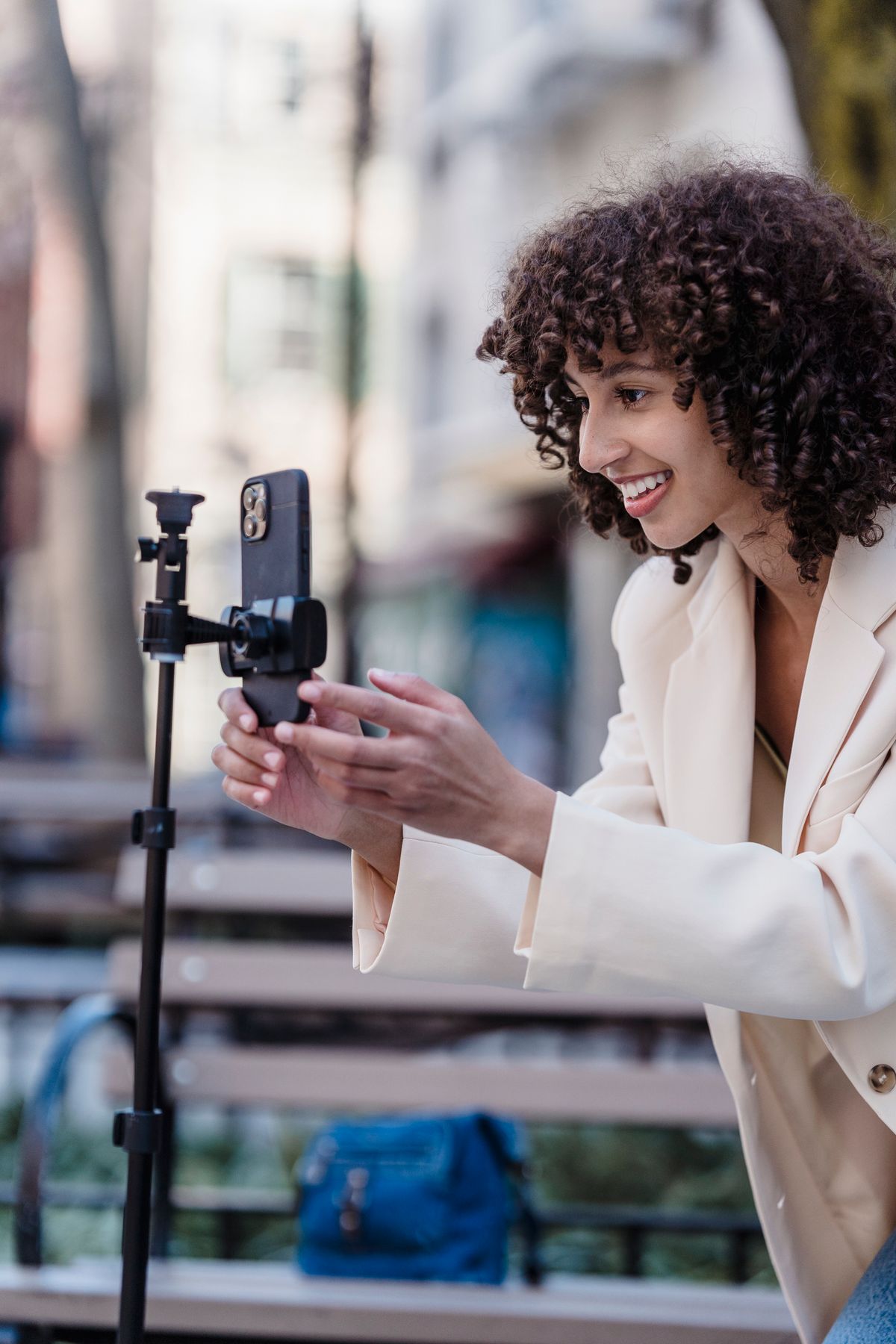 A smiling creator filming with her phone outdoors